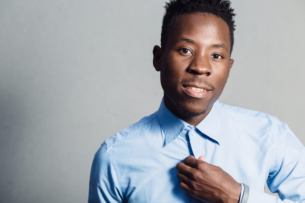 Classical portrait of african american man in blue shirt at grey wall background